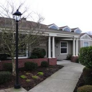 A residential house with a pathway leading to the entrance, surrounded by landscaped bushes.