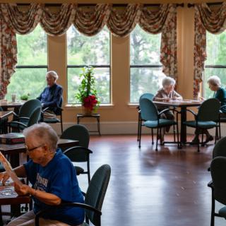 Elderly individuals relaxing and socializing in a community room setting.