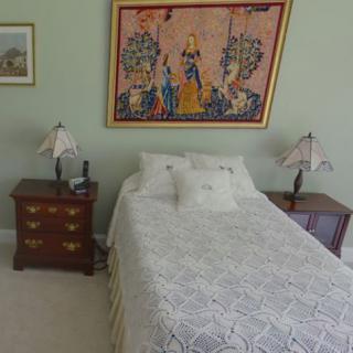 A cozy bedroom with a bed, nightstands, and decorative artwork on the wall.