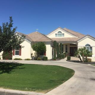 A beautiful single-story house with a well-maintained front lawn and curved driveway.