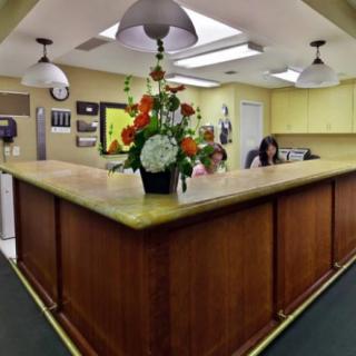 A well-lit office reception area featuring a large wooden desk with a bouquet of flowers.