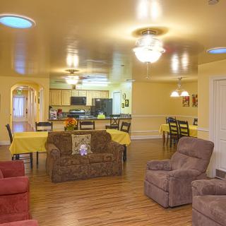 A cozy open-concept living and dining area featuring comfortable seating, a spacious kitchen, and warm yellow color tones.