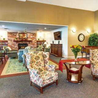A cozy living room with floral armchairs, a fireplace, and warm decor.