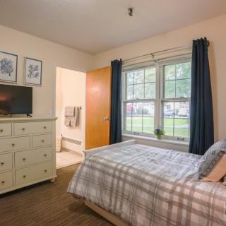 A cozy bedroom with a bed, dresser, and window, featuring soft lighting and neutral decor.