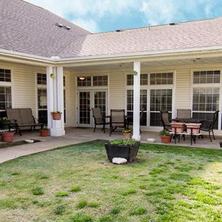 A cozy patio area with outdoor furniture and a small lawn, surrounded by a building's exterior.
