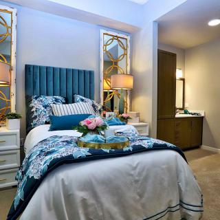 A cozy bedroom with a stylish bed, decorative pillows, and elegant lamps.