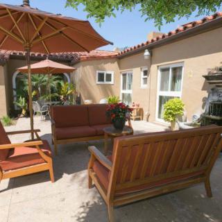 A sunny backyard patio with comfortable outdoor seating and umbrellas.