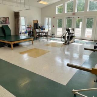 A spacious physical therapy room equipped with exercise machines and therapy tables.