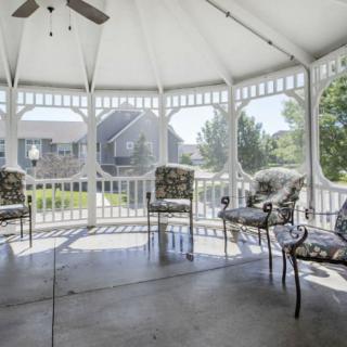 A gazebo with elegant patio furniture, providing a serene outdoor seating area on a sunny day.