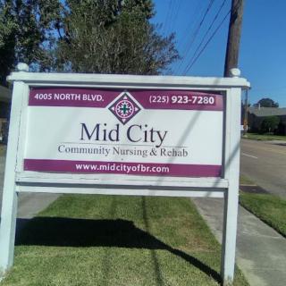 Sign for Mid City Community Nursing & Rehab located on a grassy area by the roadside.