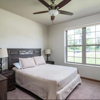 A minimalist bedroom with a bed, ceiling fan, and large window.