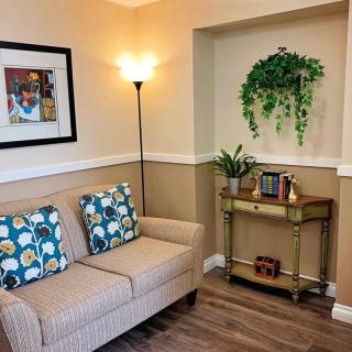 A cozy living room corner with a sofa, decorative pillows, wall art, and plants.