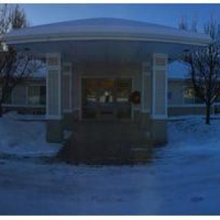 A building entrance surrounded by snow during the evening.