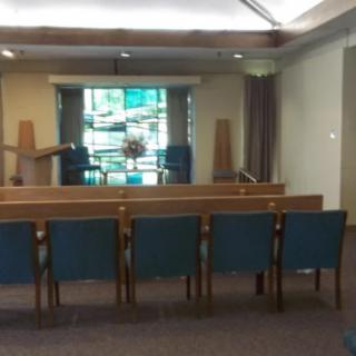 Interior of a church featuring pews, an altar, and stained glass windows.
