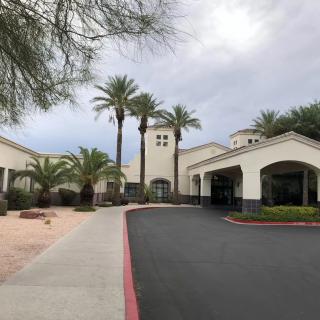 A building with palm trees and a driveway leading to the entrance.