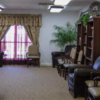 A cozy waiting room with leather chairs, bookshelves, and large windows with curtains.