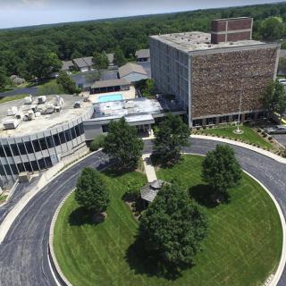 An aerial view of a building surrounded by landscaped greenery and roads.