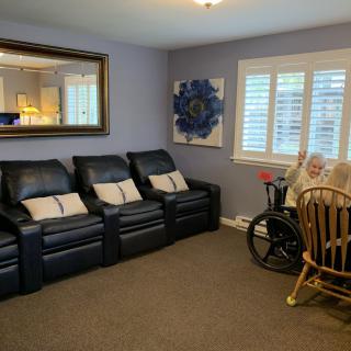A cozy living room setup with black recliner seats, a large mirror, and a wooden wheelchair.