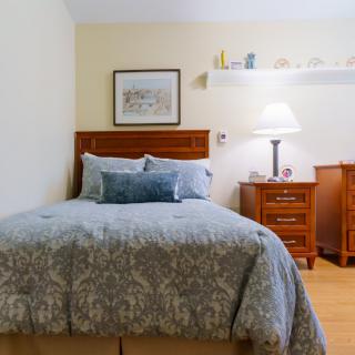 A cozy bedroom with a neatly made bed, wooden furniture, and soft lighting.