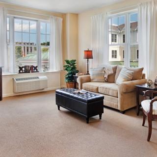 A bright and cozy living room with a sofa, coffee table, and large windows.