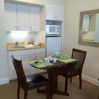 A compact kitchen area with a small dining table, chairs, and neatly arranged place settings.