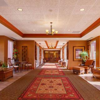 A spacious hotel lobby with a red carpet, elegant chandelier, and cozy seating area.