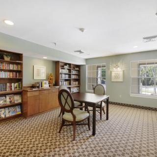 A cozy library interior with bookshelves, a reading table, and chairs.