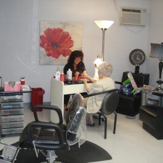 A beauty salon where a stylist is performing a manicure for a client.