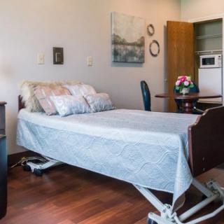 A hospital room with a single adjustable bed and simple decor.