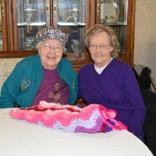 Two elderly women enjoying their time together while working on a knitting project.