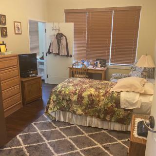 Cozy bedroom with a floral bedspread, wooden furniture, and a patterned rug.