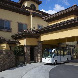 A small shuttle parked at the entrance of a large building with distinctive architecture.