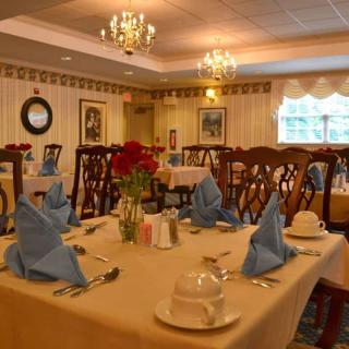 An elegantly set dining room with blue napkins and warm lighting.