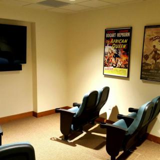 A cozy home theater room with comfortable seating and movie posters on the walls.