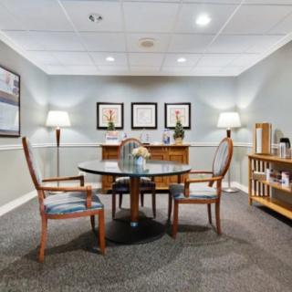 A small conference room with a round table and chairs, featuring elegant decor and framed artwork on the walls.