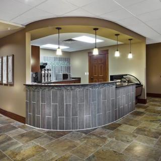 A modern office reception area with a curved desk and pendant lighting.