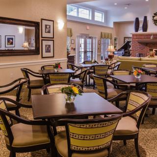 A cozy cafe with neatly arranged dining tables and chairs, featuring warm lighting and elegant decor.
