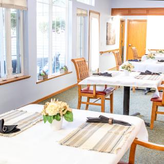 A beautifully arranged dining area, featuring tables set for guests with natural light streaming in.