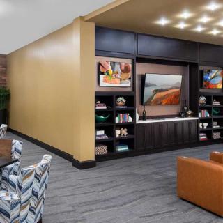A modern lounge area featuring comfortable seating, built-in bookshelves, and a large television.