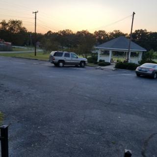 A serene evening view of a parking lot with cars and a building in the background as the sun sets.