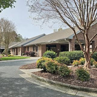 A peaceful residential building surrounded by well-maintained gardens and a welcoming driveway.