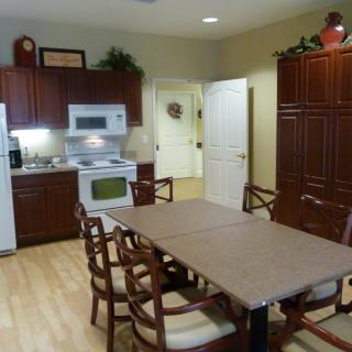 A kitchen and dining area featuring a long table with chairs, wooden cabinets, and modern appliances.