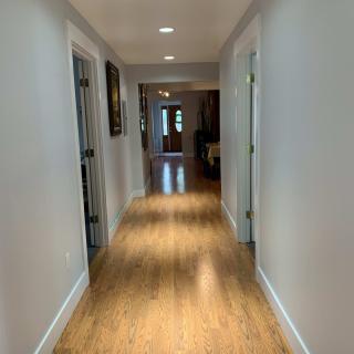 A well-lit hallway with wooden flooring and multiple doors.