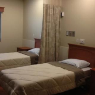 A hospital room with two neatly made beds separated by a curtain.