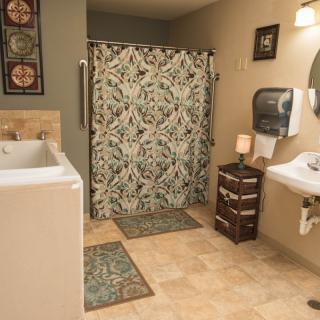 A modern bathroom with a floral shower curtain, tiled floor, and sink.