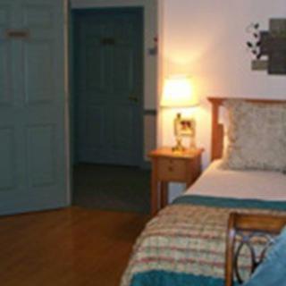 A cozy bedroom with wooden furniture and a glowing bedside lamp.