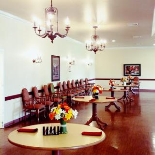 A beautifully arranged dining room with elegant chandeliers and floral centerpieces on the tables.