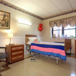 A well-lit hospital room with a neatly made bed and decorative elements.