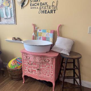 A charming vintage pink cabinet adorned with a cheerful quote, perfect for adding a touch of warmth to any room.