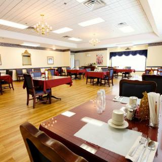 A well-lit dining room with neatly arranged tables and chairs on a wooden floor.